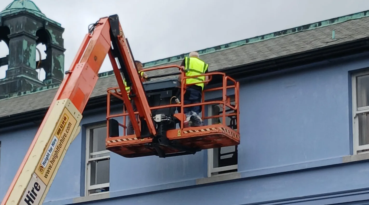 Roofers working at the roofline from an access lift